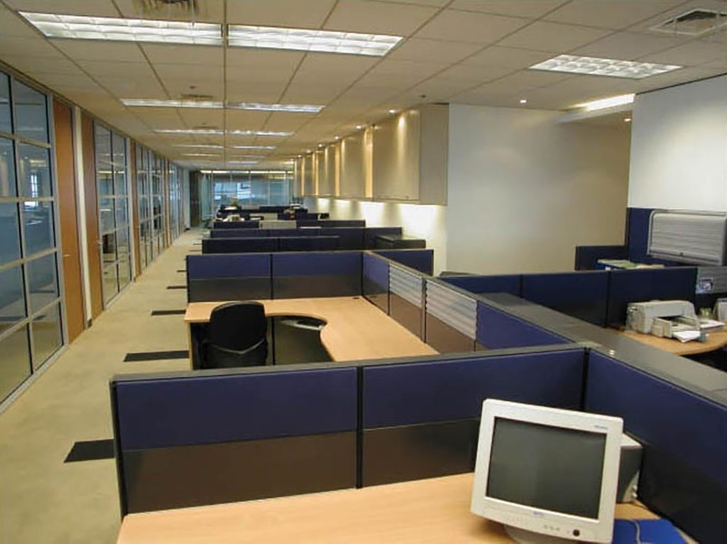 Open-plan office with modular cubicles, blue partitions, and linear lights