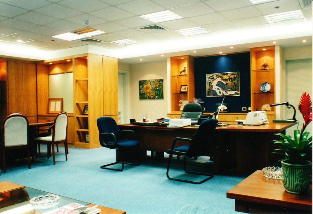 Executive office with dark wood desk, blue carpet, and built-in cabinetry