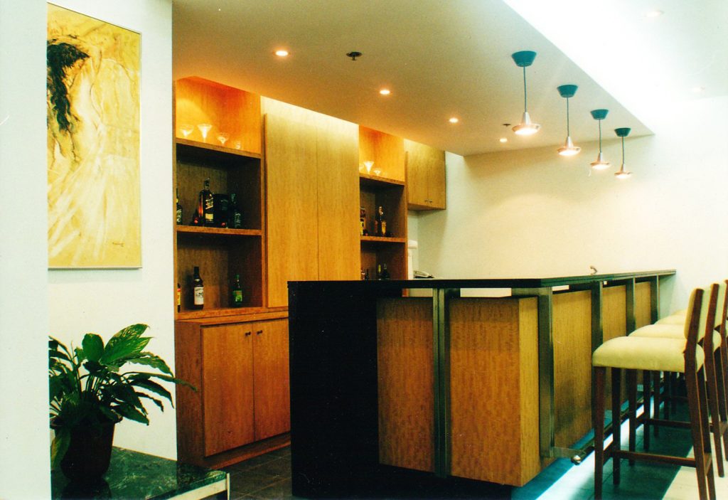Wooden bar counter with high seating, artwork, and pendant lighting