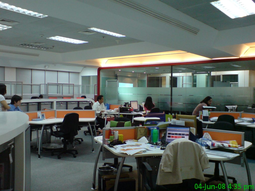 Open office with orange partitions, green chairs, and glass conference area